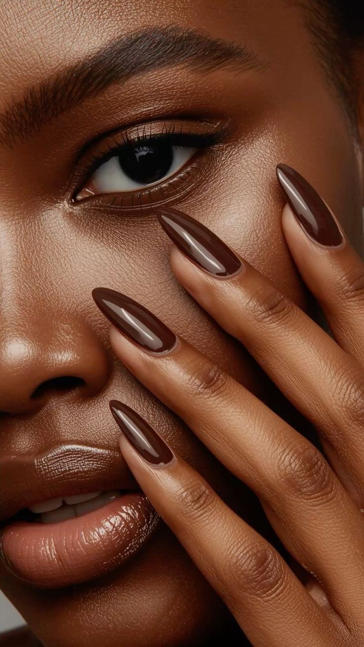 Close-up of a person with dark skin and brown nail polish