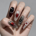 A close-up of a hand showcasing a gothic-inspired nail art design with coffin-shaped nails decorated in black, deep red, and silver metallic patterns.
